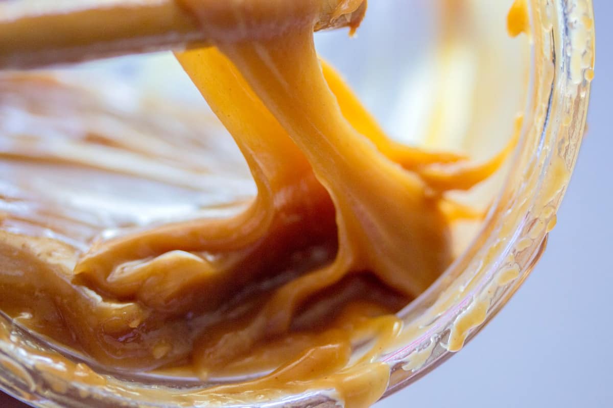 Thick amber caramel flowing off a beater