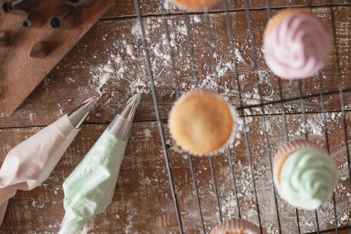 Frosting being piped onto a cupcake with a piping bag