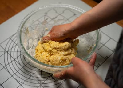 Cold butter being rubbed into flour until crumbly